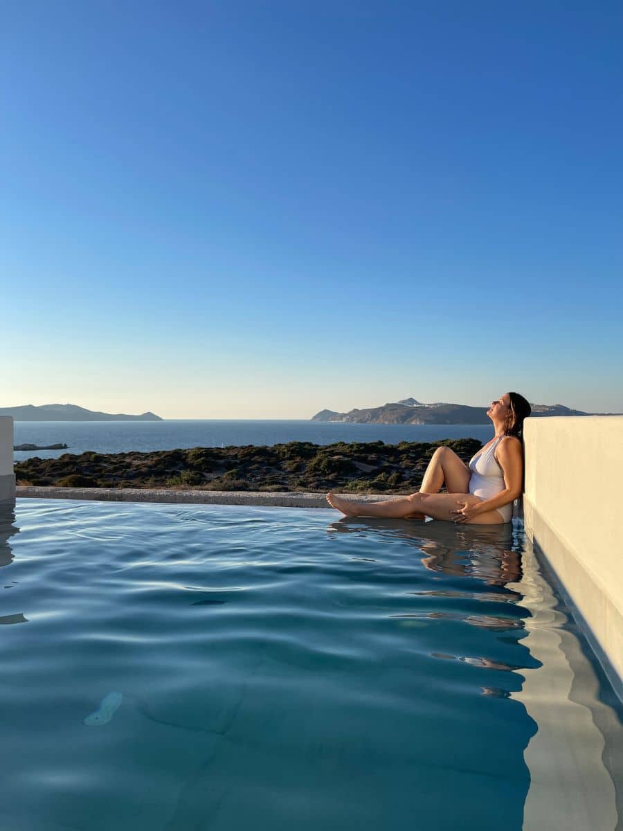 A woman sitting on the edge of a pool in Milos