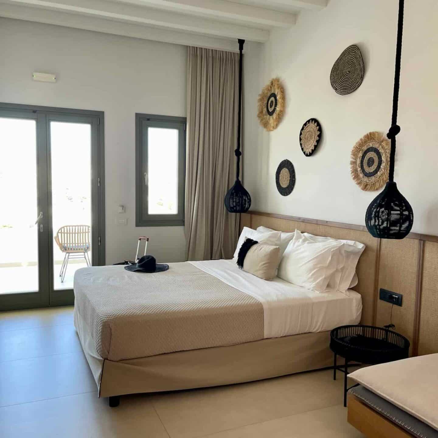 A stylish and inviting hotel bedroom featuring a comfortable bed with chic décor and a balcony view