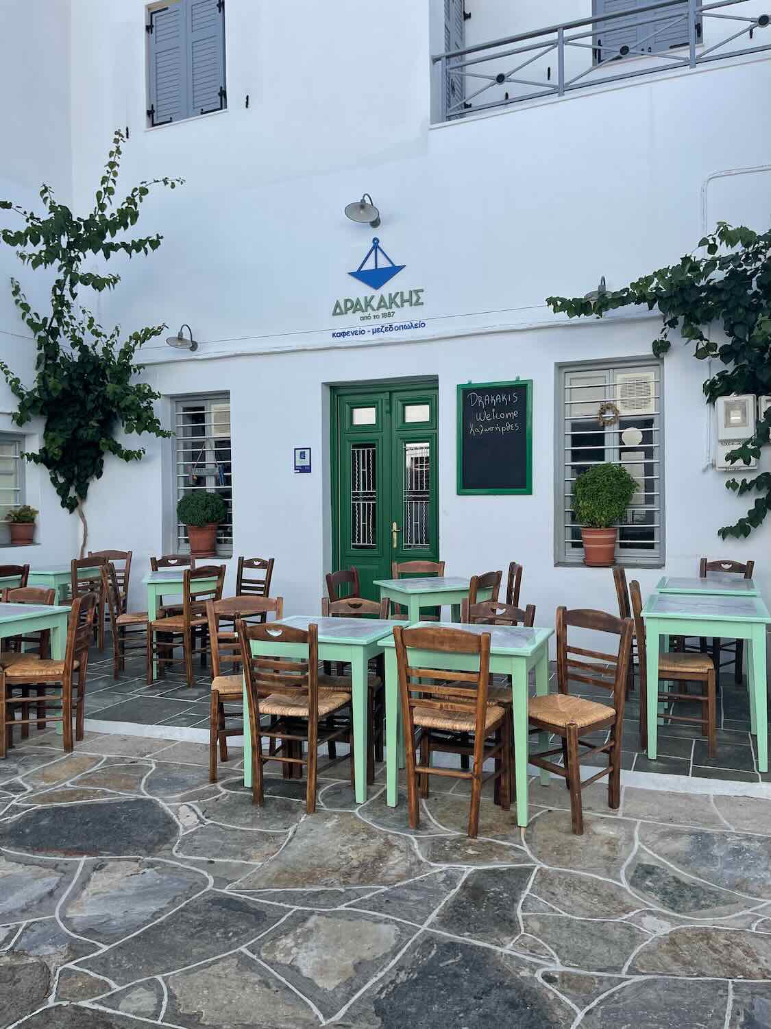 A cozy outdoor café in Sifnos with mint green chairs and wooden tables, inviting visitors to relax and dine.