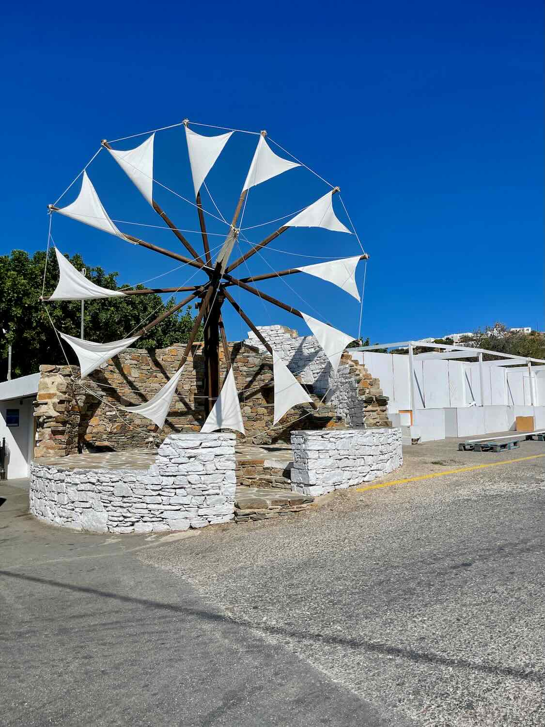 A restored traditional windmill in Sifnos with white and blue sails, standing as a symbol of the island's heritage, a unique sight on a Sifnos.