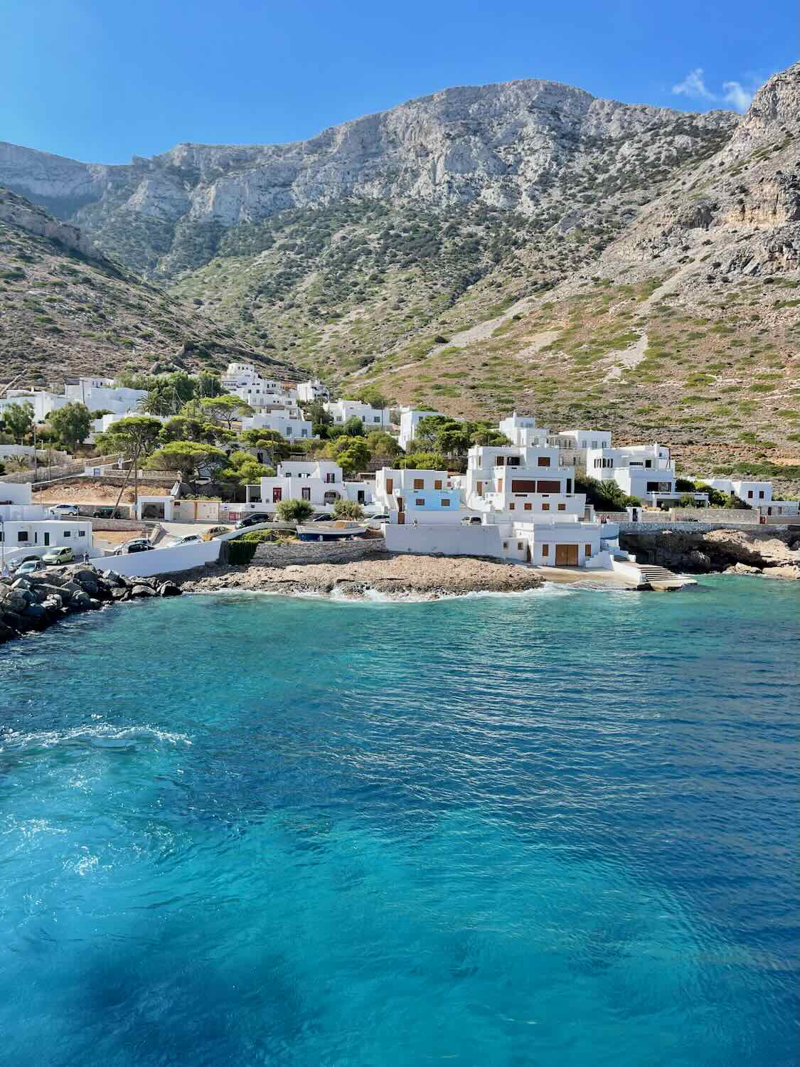 he picturesque port of Sifnos, with white buildings against a backdrop of rugged mountains and the clear Aegean Sea.
