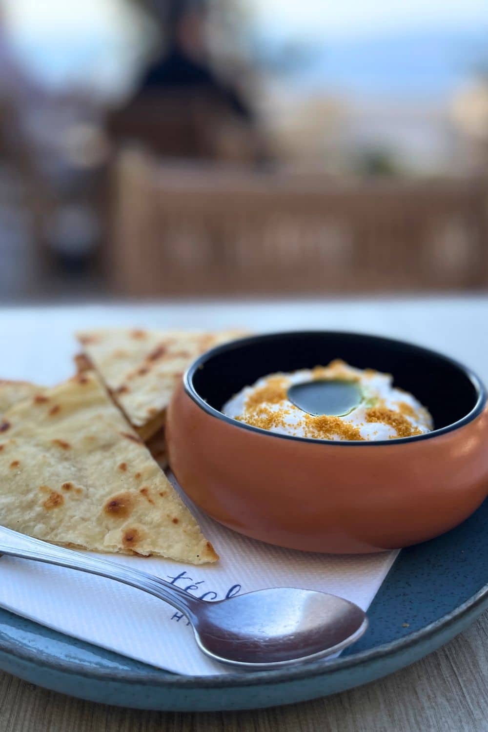 Close-up of a traditional Greek appetizer, taramasalata, served in a terracotta bowl with flatbread on a ceramic plate, ready for a taste of Hydra's local cuisine