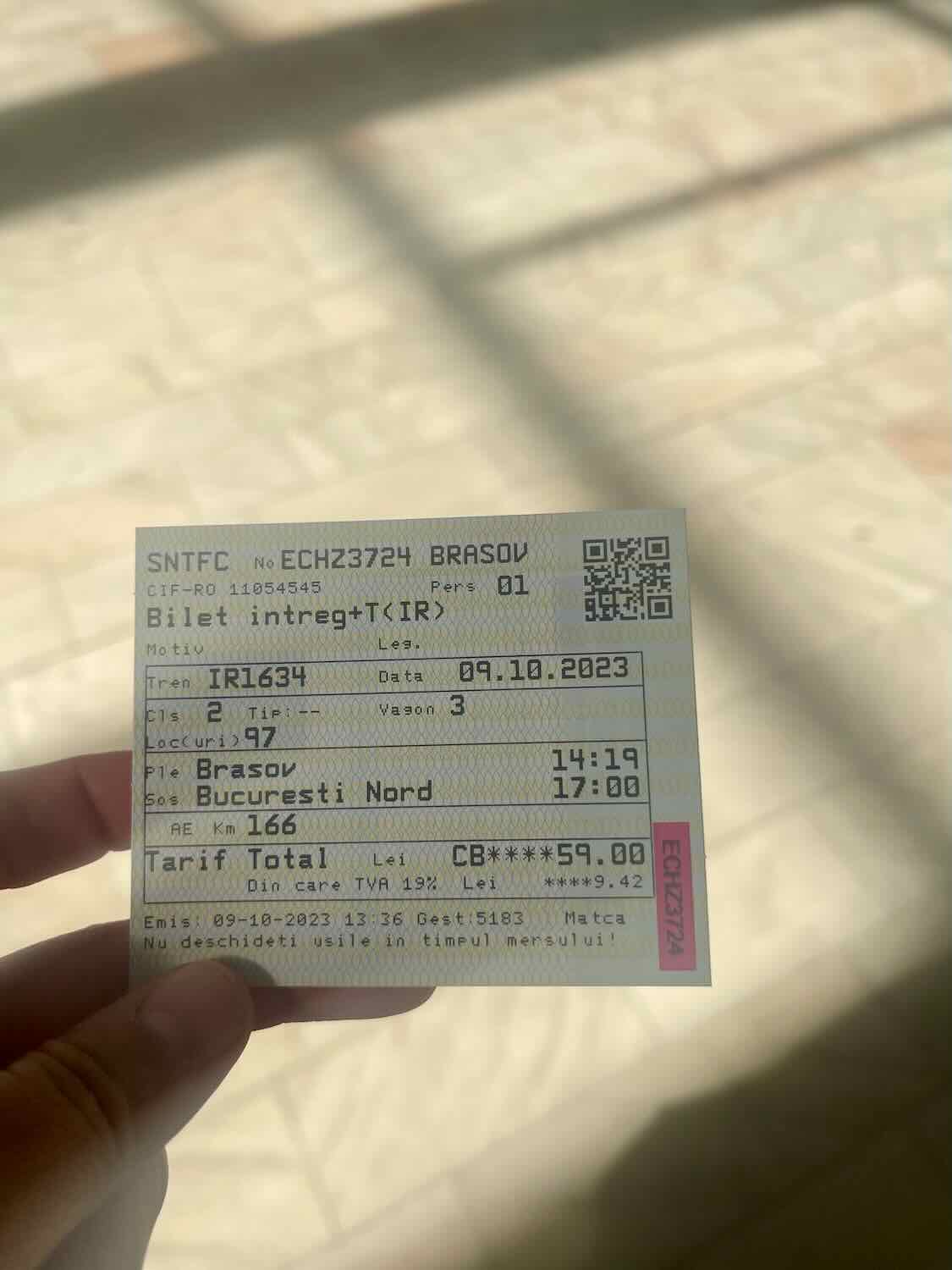 A person's hand holding a train ticket from Bucharest to Brasov, with details of the journey and the date, emphasizing the travel aspect of the blogger's experience.