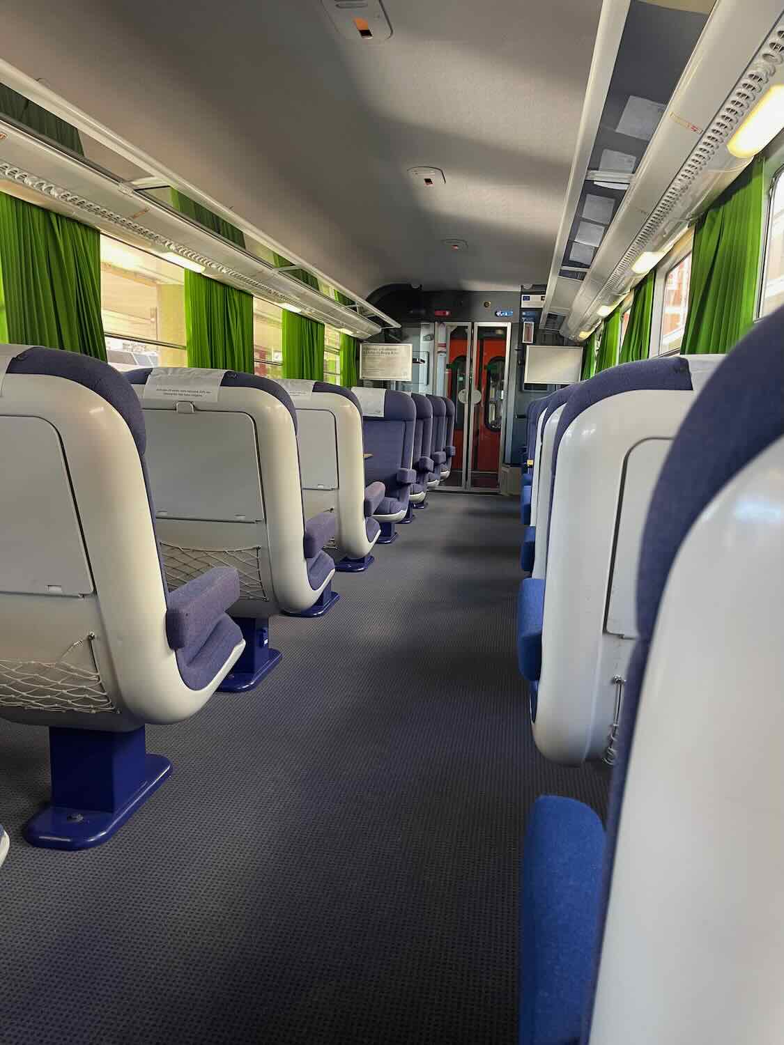 Inside view of a comfortable train carriage with blue and white seats ready to welcome passengers on the journey from Lisbon to Faro for a delightful day trip.