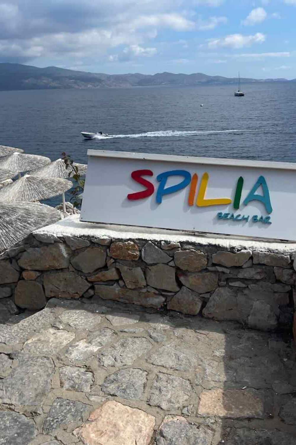 The colorful sign of Spilia Beach Bar against a backdrop of the sea in Hydra, capturing the essence of a laid-back Greek island getaway.