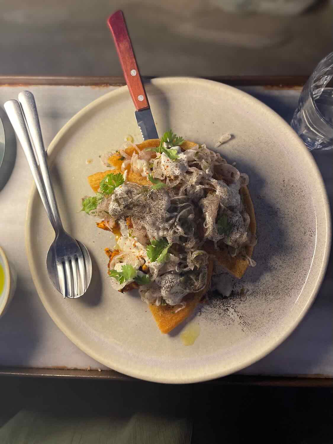 A savory local dish served in Sifnos, garnished with fresh herbs and a side of cutlery, reflecting the island's gastronomic offerings