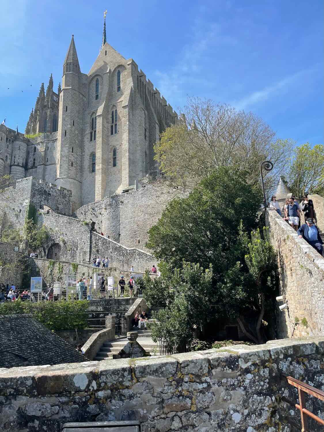 Majestic view of Mont Saint Michel Abbey towering above on rocky foundations, set against a brilliant blue sky.