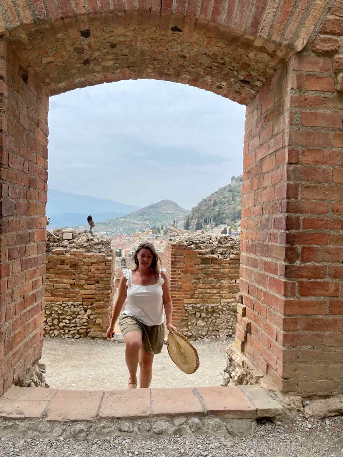 A woman walking the a doorway at the ancient theatre in Taormina. 