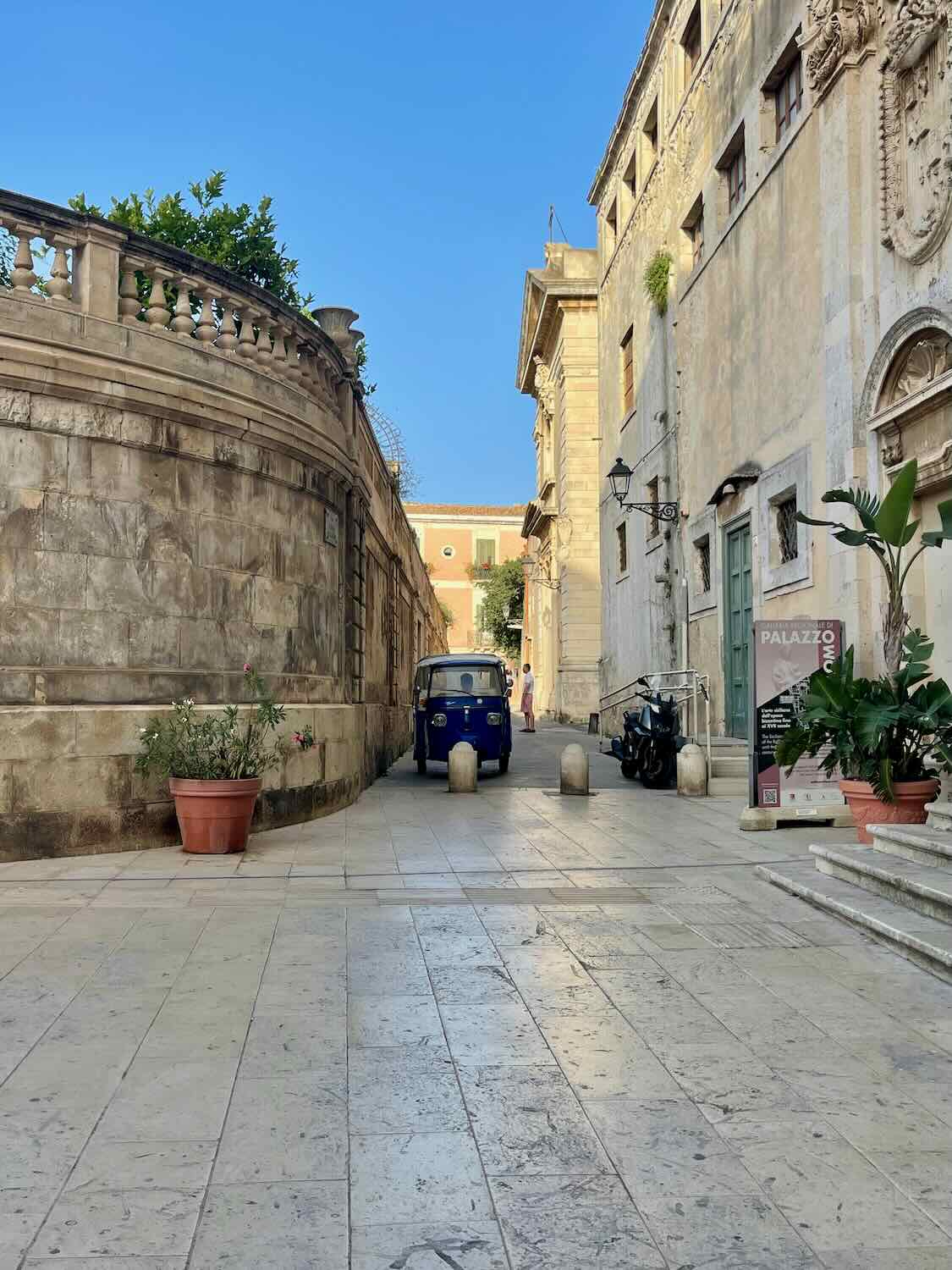 Picture of a stone wall and small car within the old town of Siracusa