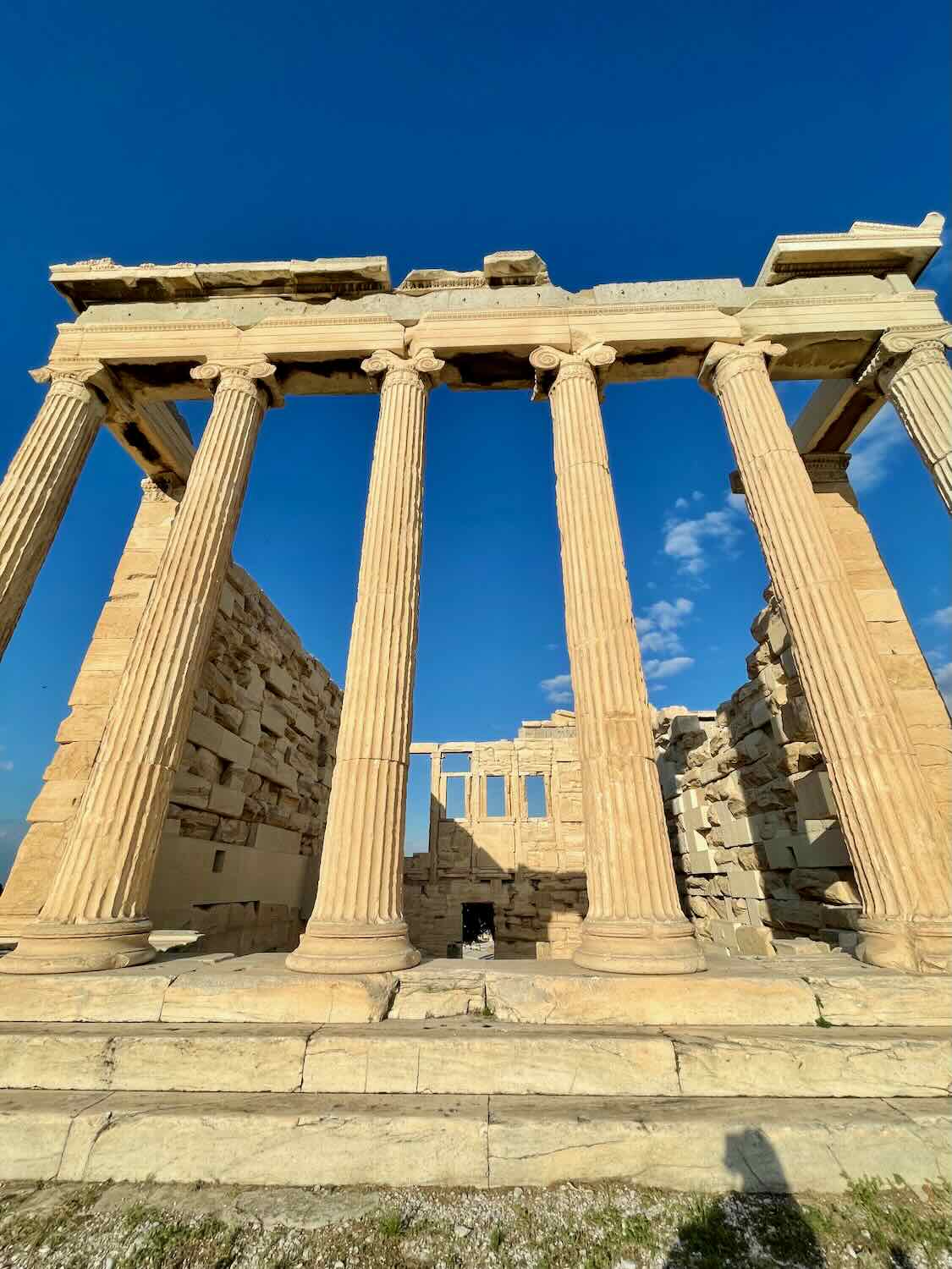 A photo of the Erechtheion, an ancient Greek temple with tall columns, situated on the Acropolis of Athens under a clear blue sky.
