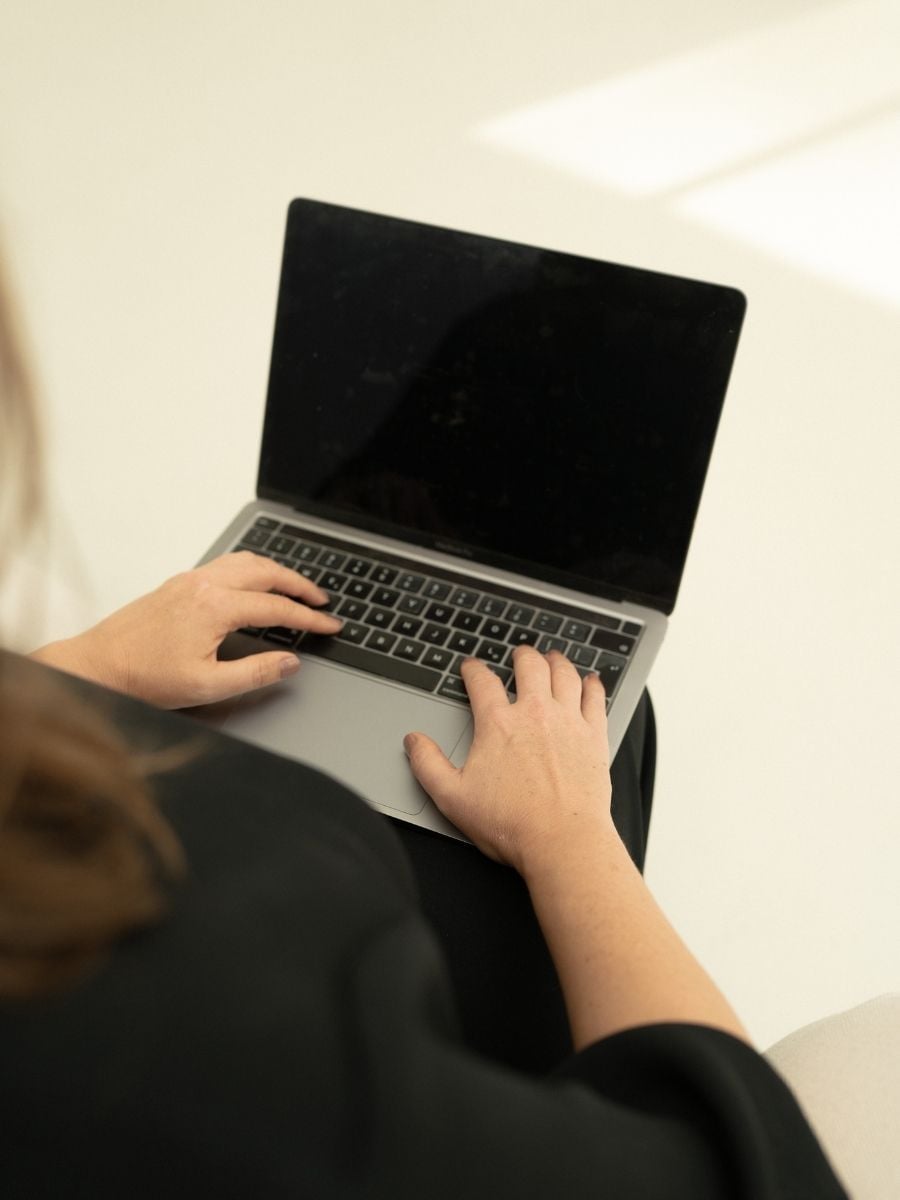 Melissa Byron, founder of A Solo Woman Traveling, typing on a laptop while managing her travel business.