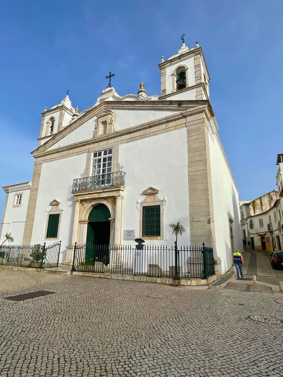 Igreja de Santa Maria in Lagos, a whitewashed 15th-century church with twin bell towers and a cobblestone square in front