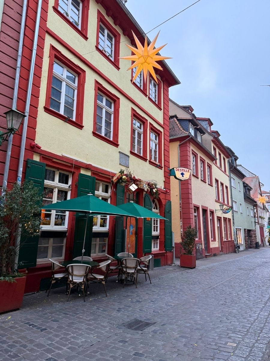 Bright red and yellow building with green shutters, outdoor seating, and a festive star decoration above.
