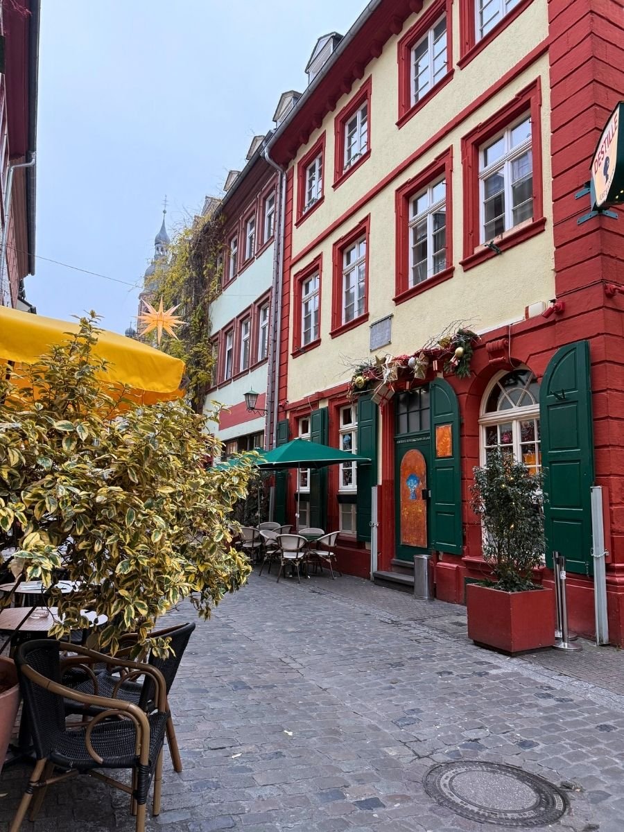 Cozy street café with yellow and green umbrellas and decorated building exteriors.