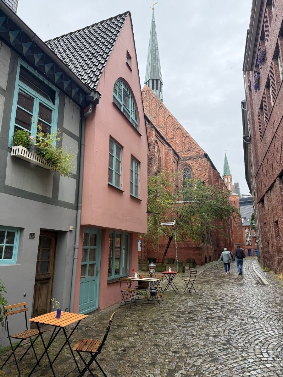 Charming cobblestone street in Bremen’s Schnoor quarter with colorful houses and café tables.
