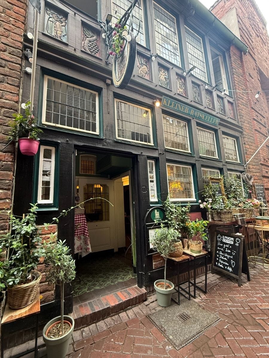 Decorative facade of Kleiner Ratskeller restaurant with plants and signage in Bremen, Germany.