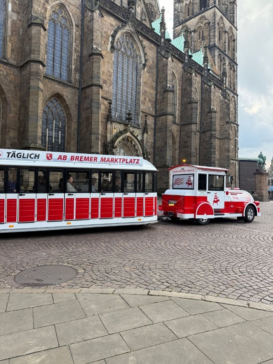 Red and white tourist train parked in front of Bremen Cathedral (St. Petri Dom) at Bremer Marktplatz in Bremen, Germany.
