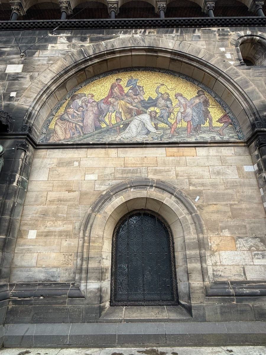 A detailed view of the golden mosaic above one of the arched doors of Bremen Cathedral (St. Petri Dom), depicting a biblical scene in vibrant colors.