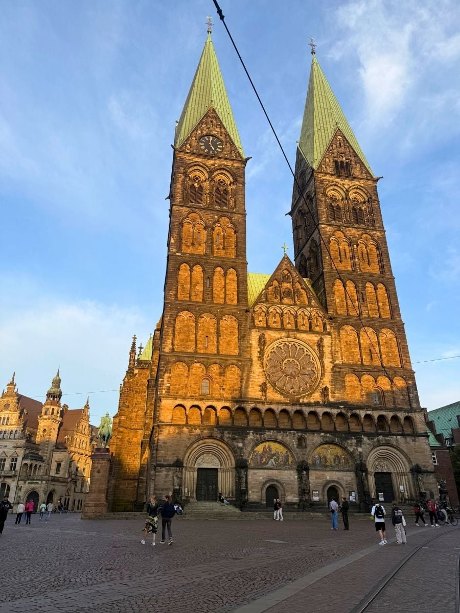 The twin spires of St. Peter&rsquo;s Cathedral in Bremen illuminated by golden evening light on the Marktplatz.