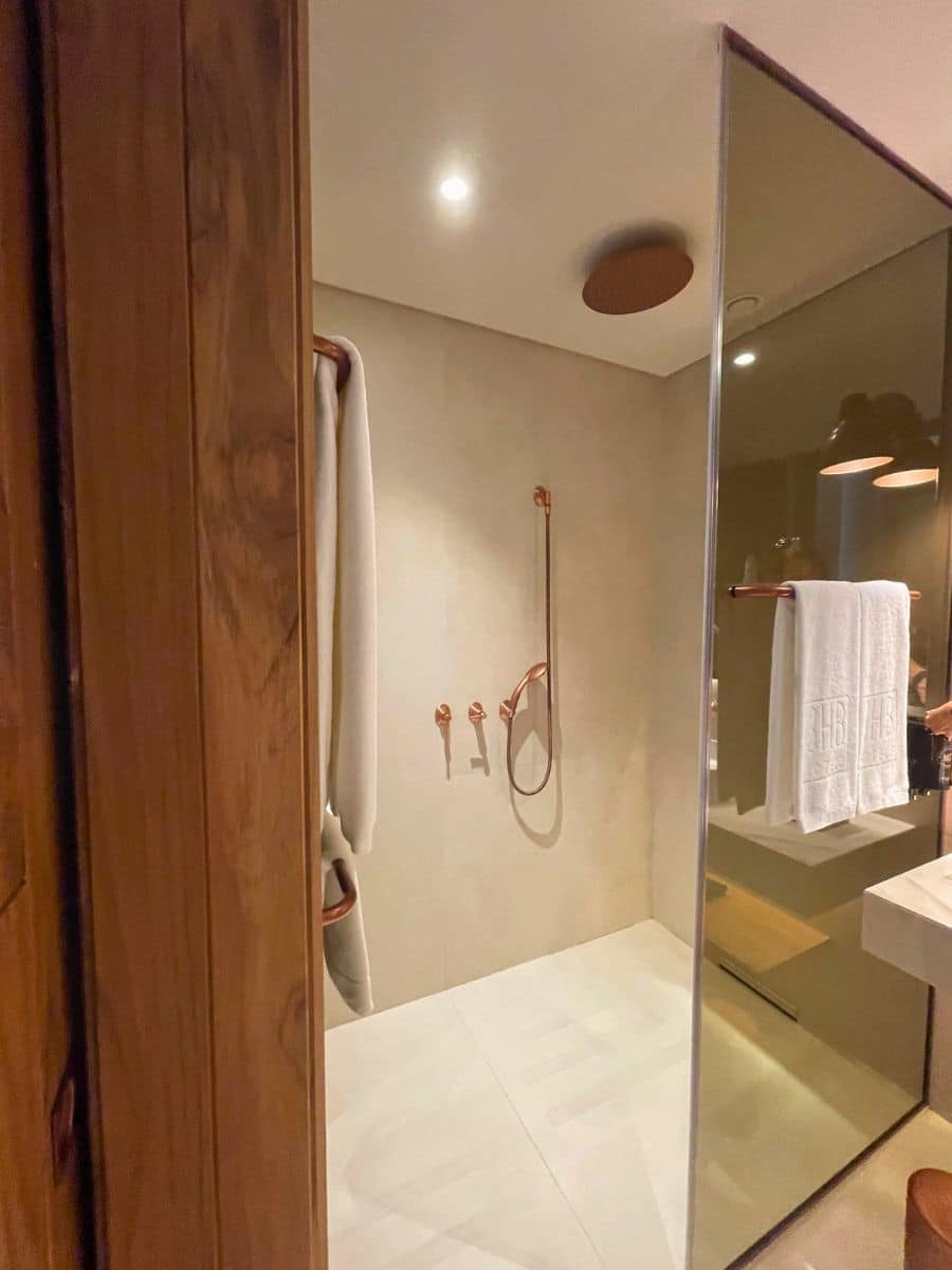 Walk-in shower with sleek copper fixtures and minimal design at 3HB Faro.