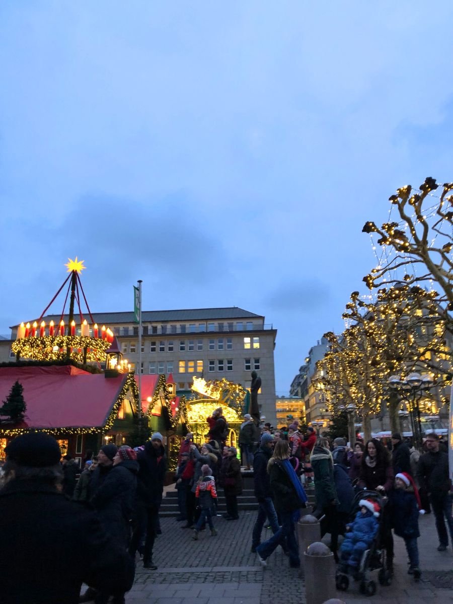 Crowds enjoying the festive atmosphere at the Hamburg Christmas Market with decorated stalls and glowing lights.