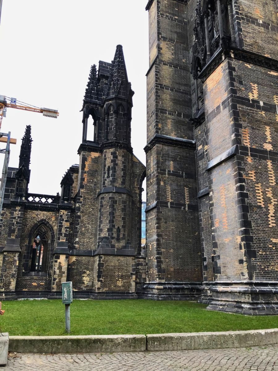 Close-up of the striking Gothic ruins of St. Nikolai Church in Hamburg. The weathered dark bricks and towering spires tell a story of resilience and history, standing tall as a powerful reminder of the city’s past.