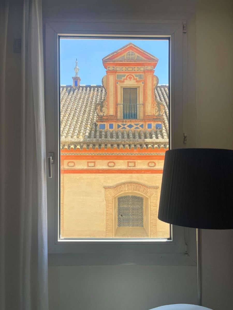 View from a guest room window of a traditional Seville building with colorful details and tiled roof.