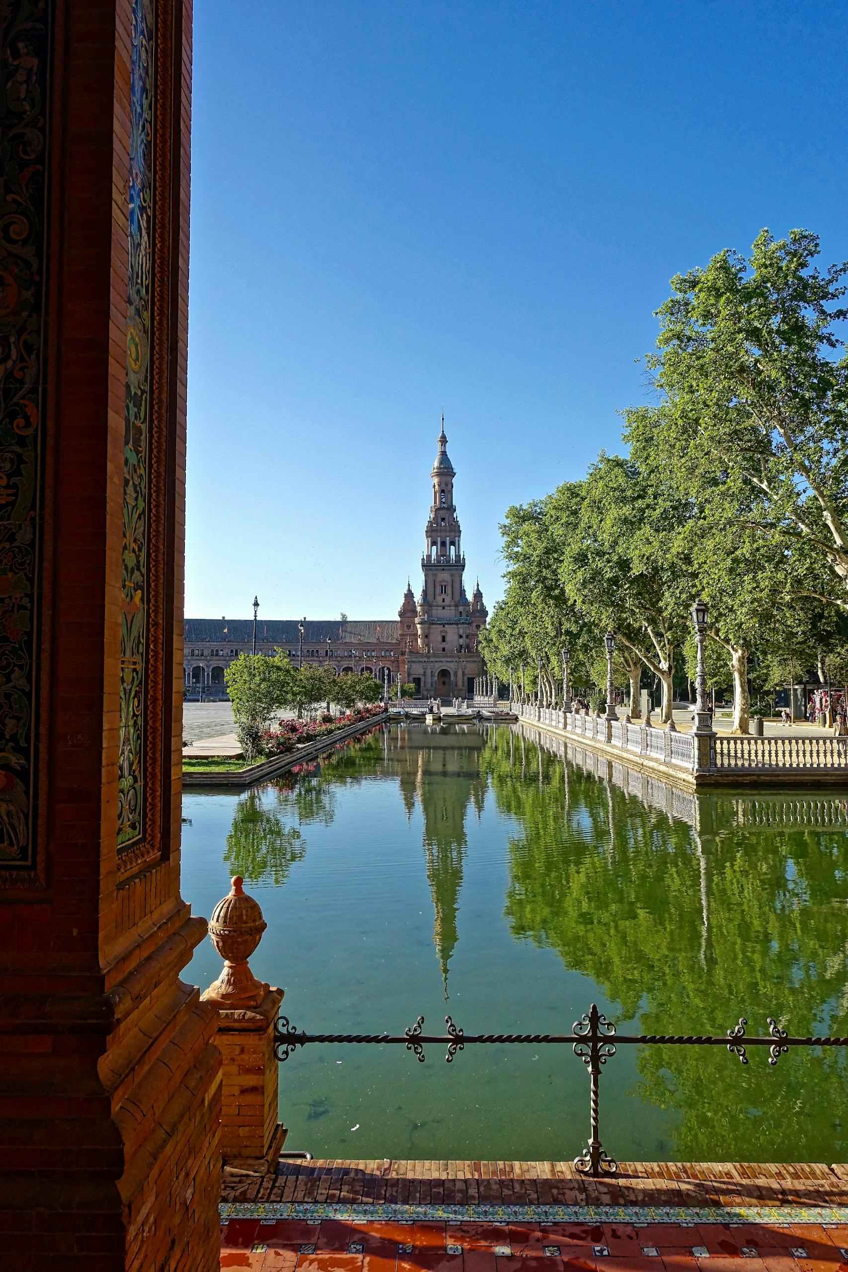 Historic Plaza de España in Seville featuring water reflections and classic architecture.