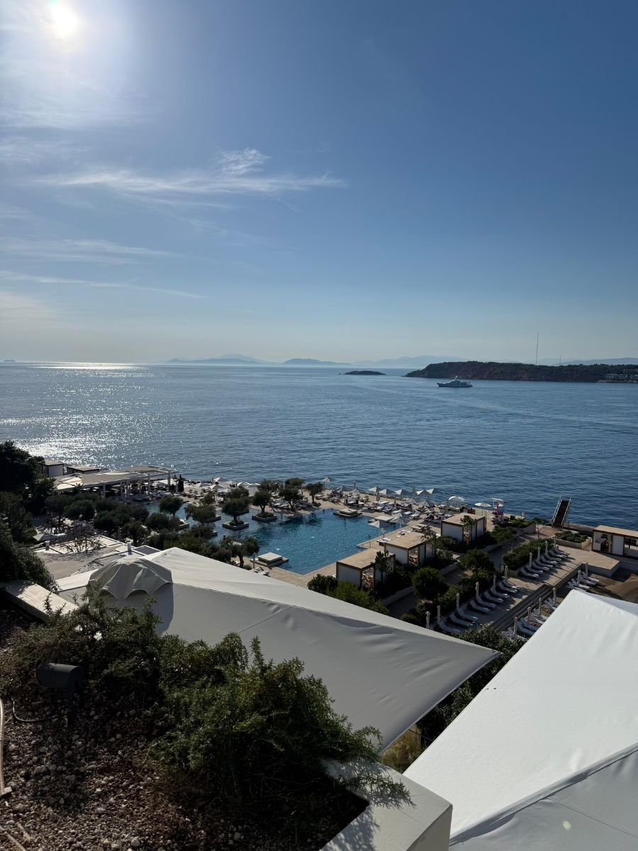 Luxury seaside resort pool overlooking the Aegean Sea with sun loungers and coastal view at Vouliagmeni, Athens Riviera.