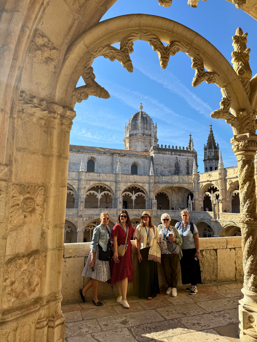 Group of women framed by an arched window inside Jer&oacute;nimos Monastery&rsquo;s upper cloisters in Lisbon, Portugal