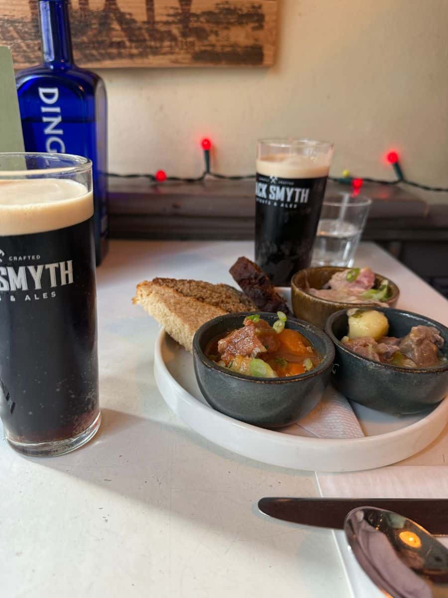 A tasting plate of mini Irish stews served with homemade bread and dark beer at a Dublin pub.