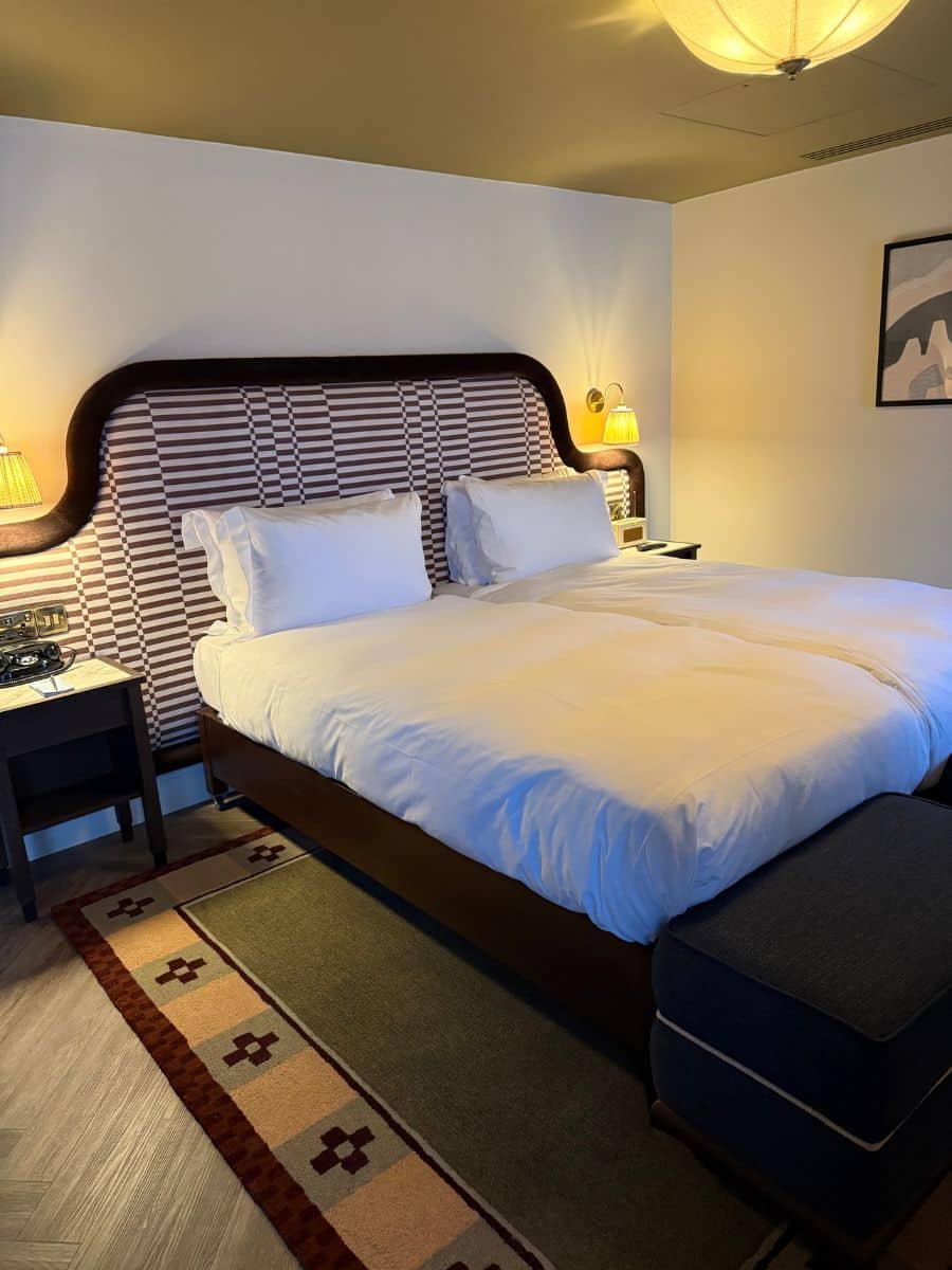 Elegant hotel room in Ireland with a large king bed, patterned headboard, warm lighting, and a modern design.