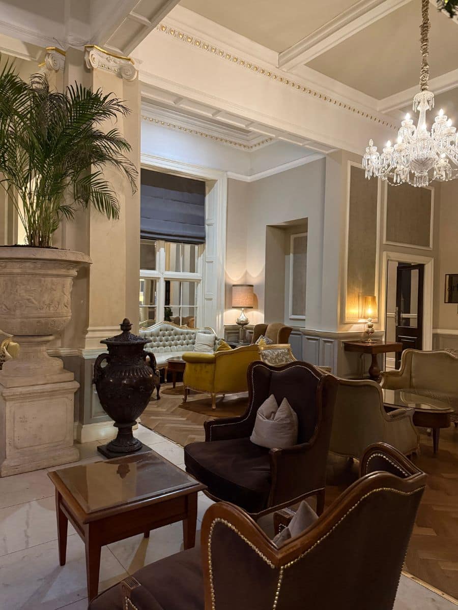 Luxurious hotel lounge with velvet armchairs, chandeliers, and classic d&eacute;cor, creating an elegant and cozy atmosphere.