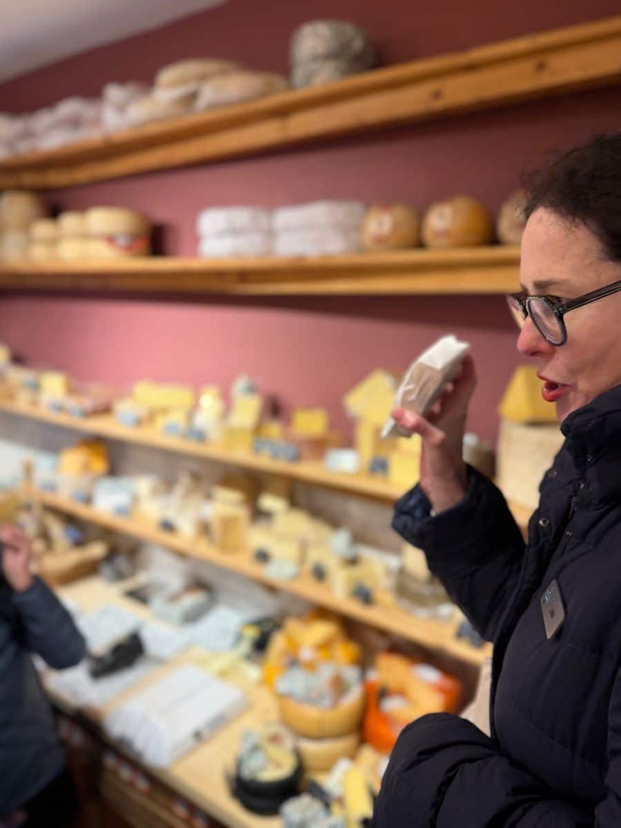 A guide presenting a piece of cheese during a tasting inside an artisanal Irish cheese shop.