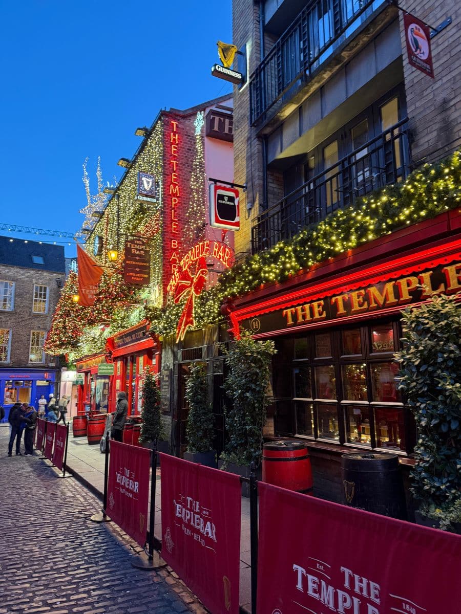 Temple Bar in Dublin lit up with festive lights, showing the vibrant nightlife and iconic red fa&ccedil;ade.