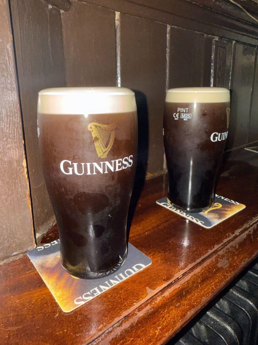 Two freshly poured pints of Guinness resting on a wooden pub counter in Dublin.