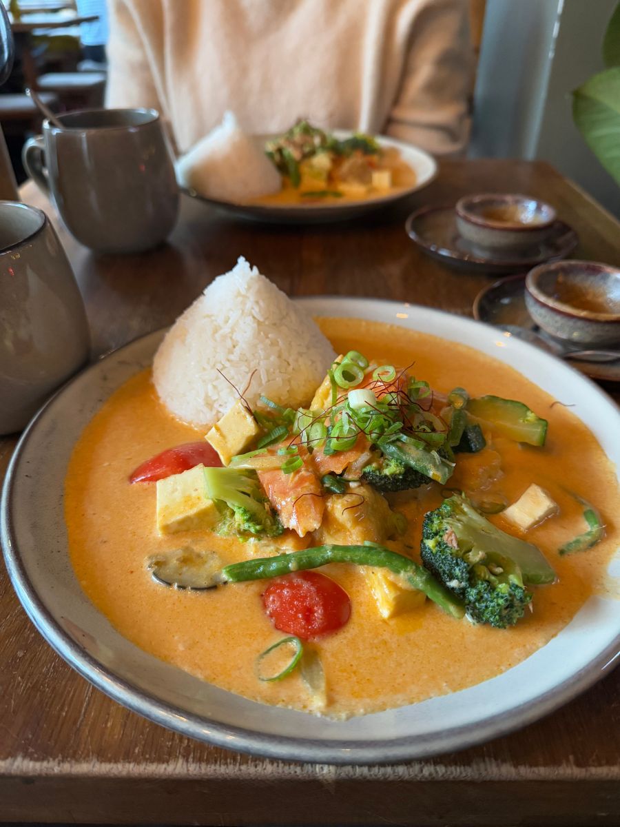 Plate of colorful Thai red curry with rice pyramid and vegetables served at Soy, a vegan Asian restaurant in Berlin.