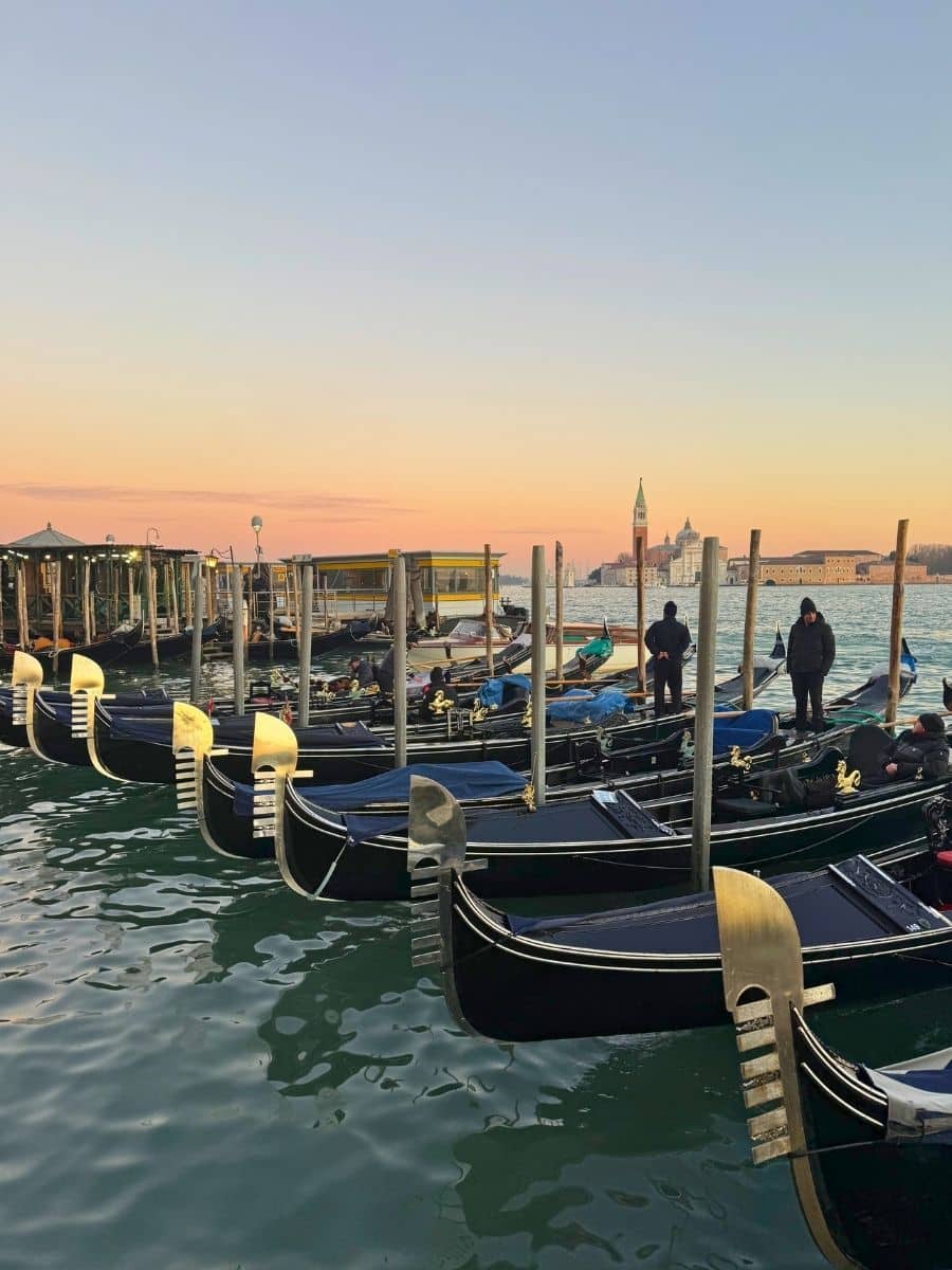 Gondolas lined up on the water at sunset in Venice, Italy.