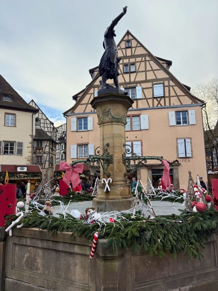 Decorated town fountain with Christmas ornaments and medieval statue in Colmar old town, France
