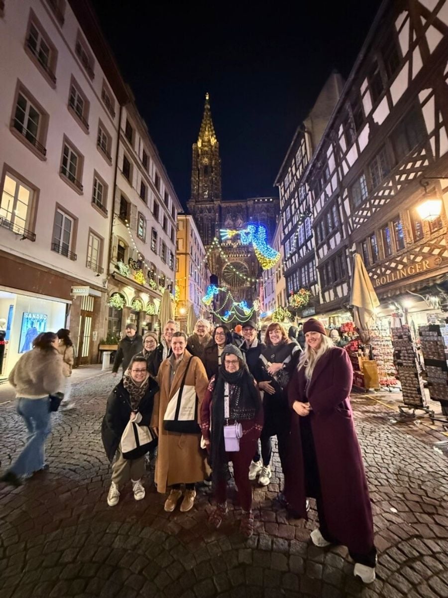 Group of women posing at night on Strasbourg street with cathedral and Christmas lights in the background