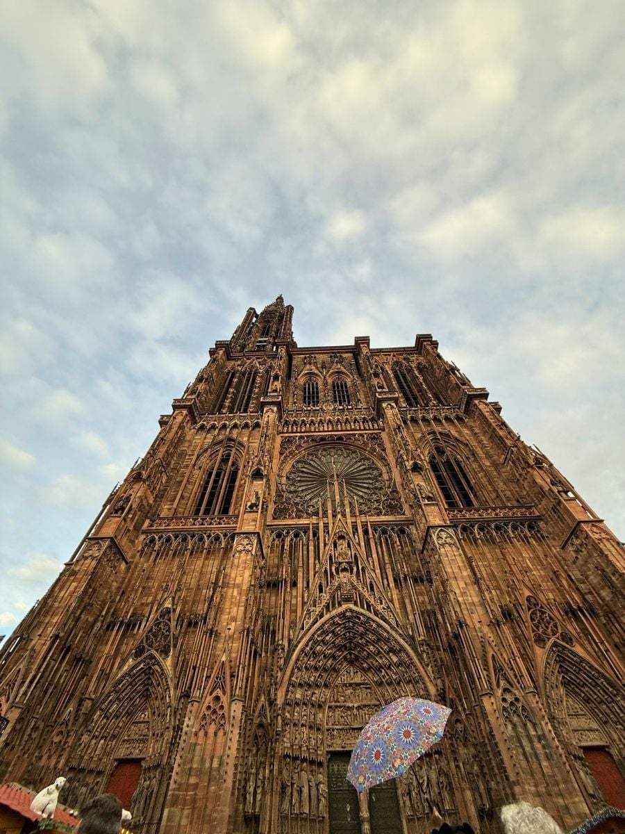 Strasbourg Cathedral facade viewed from below with intricate Gothic details and cloudy sky
