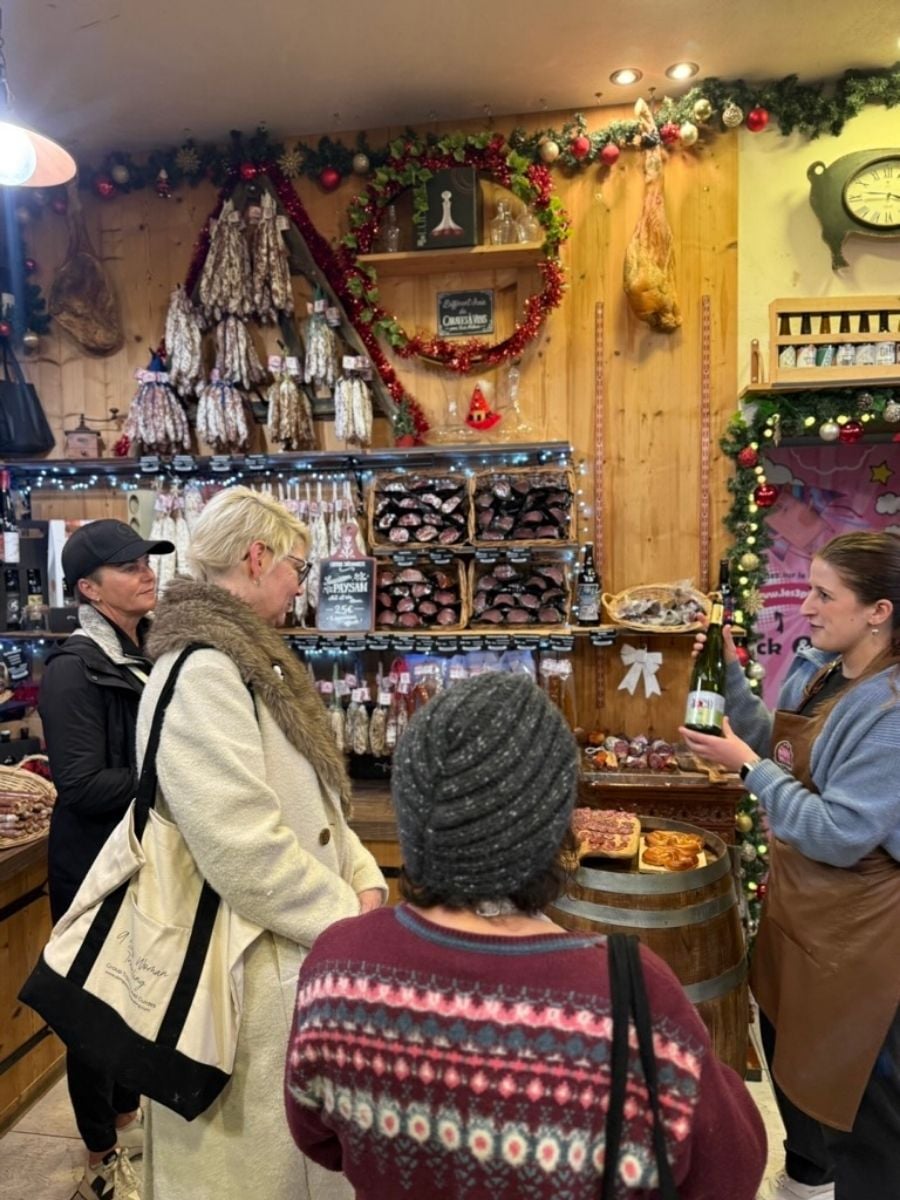 Shoppers browsing cured meats and wine inside festive Strasbourg Christmas market stall