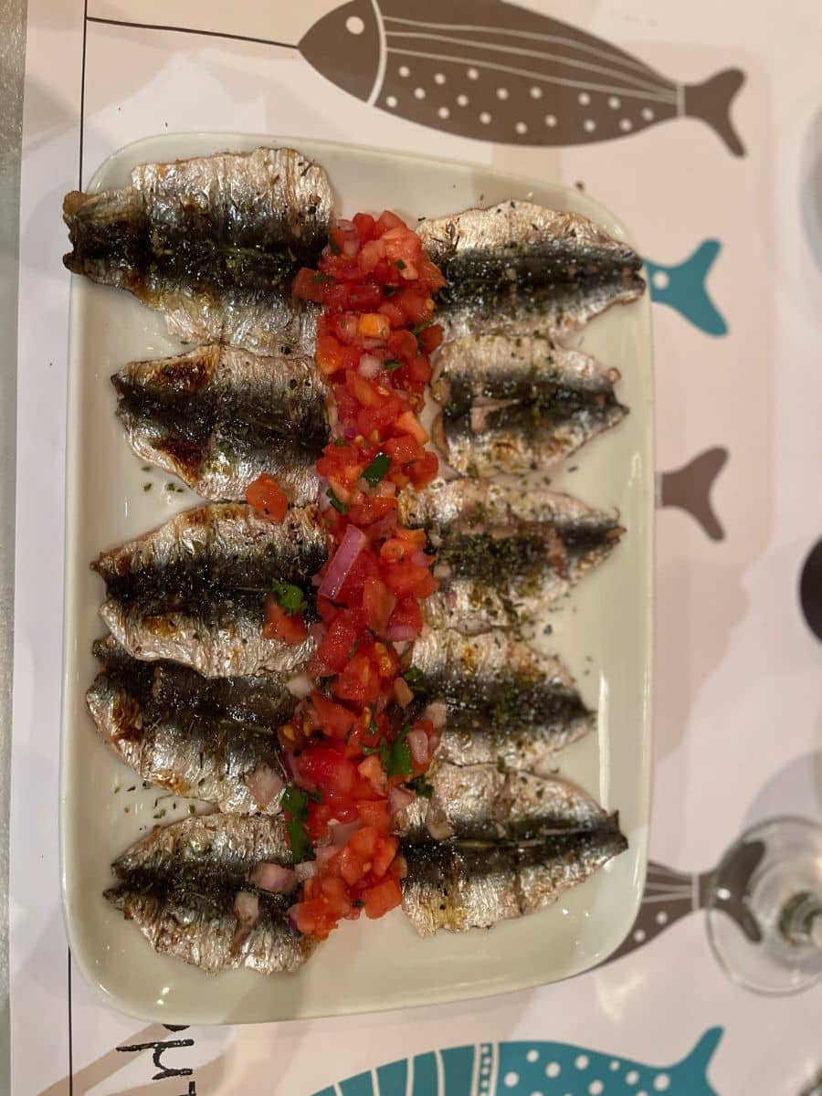 Grilled sardines topped with fresh tomato salsa served during a traditional Athens food tour.