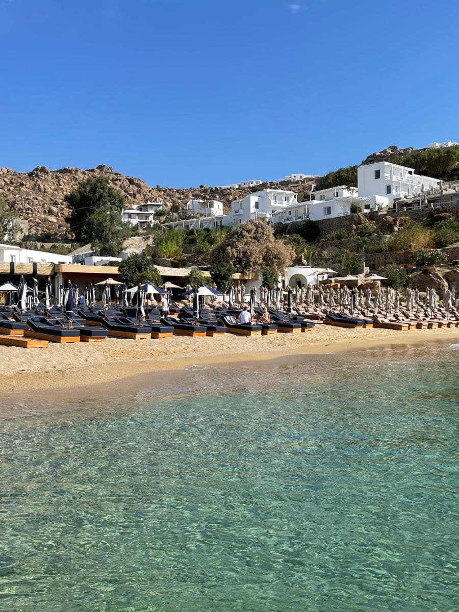Luxury beach club with sunbeds and clear turquoise water on a beach in Mykonos