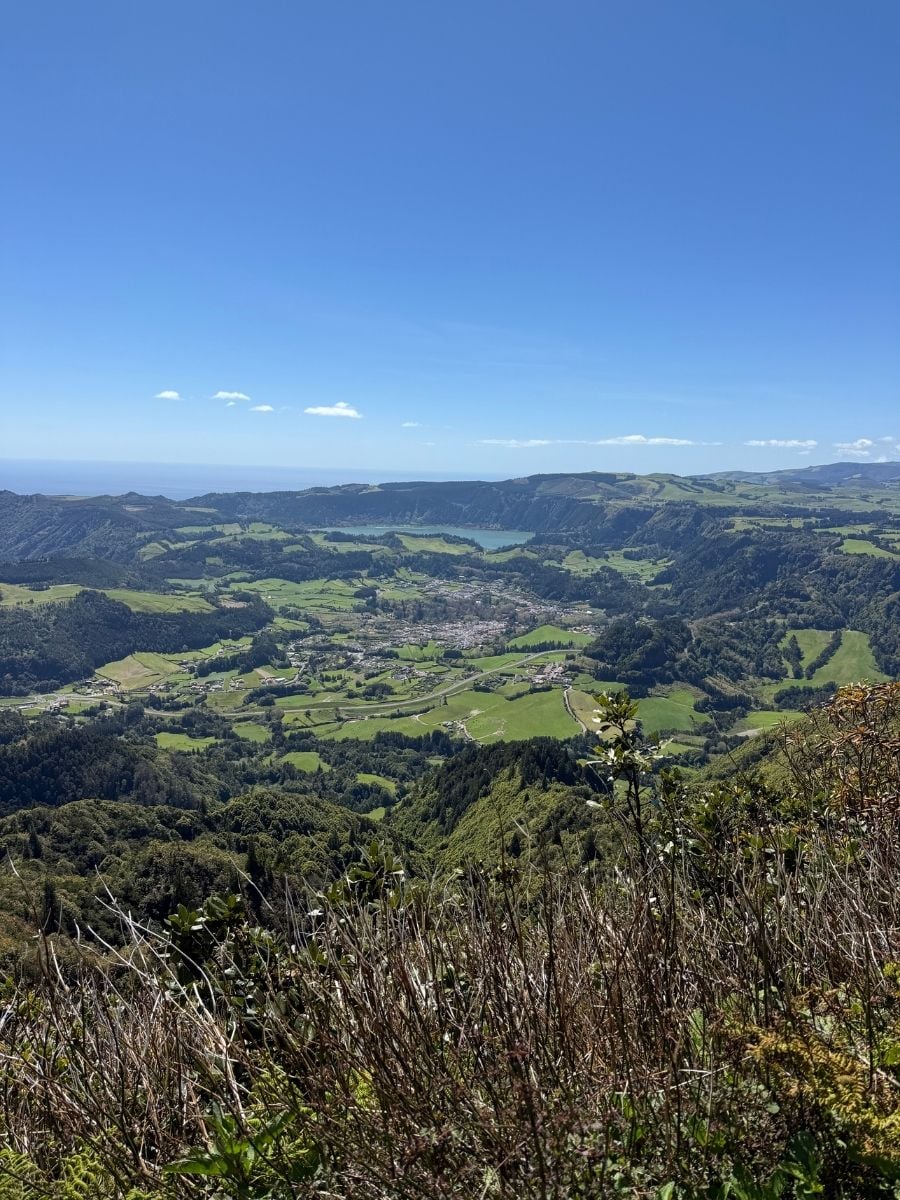 Panoramic valley view in S&atilde;o Miguel, Azores with patchwork green fields, a small town, and the Atlantic Ocean visible in the distance