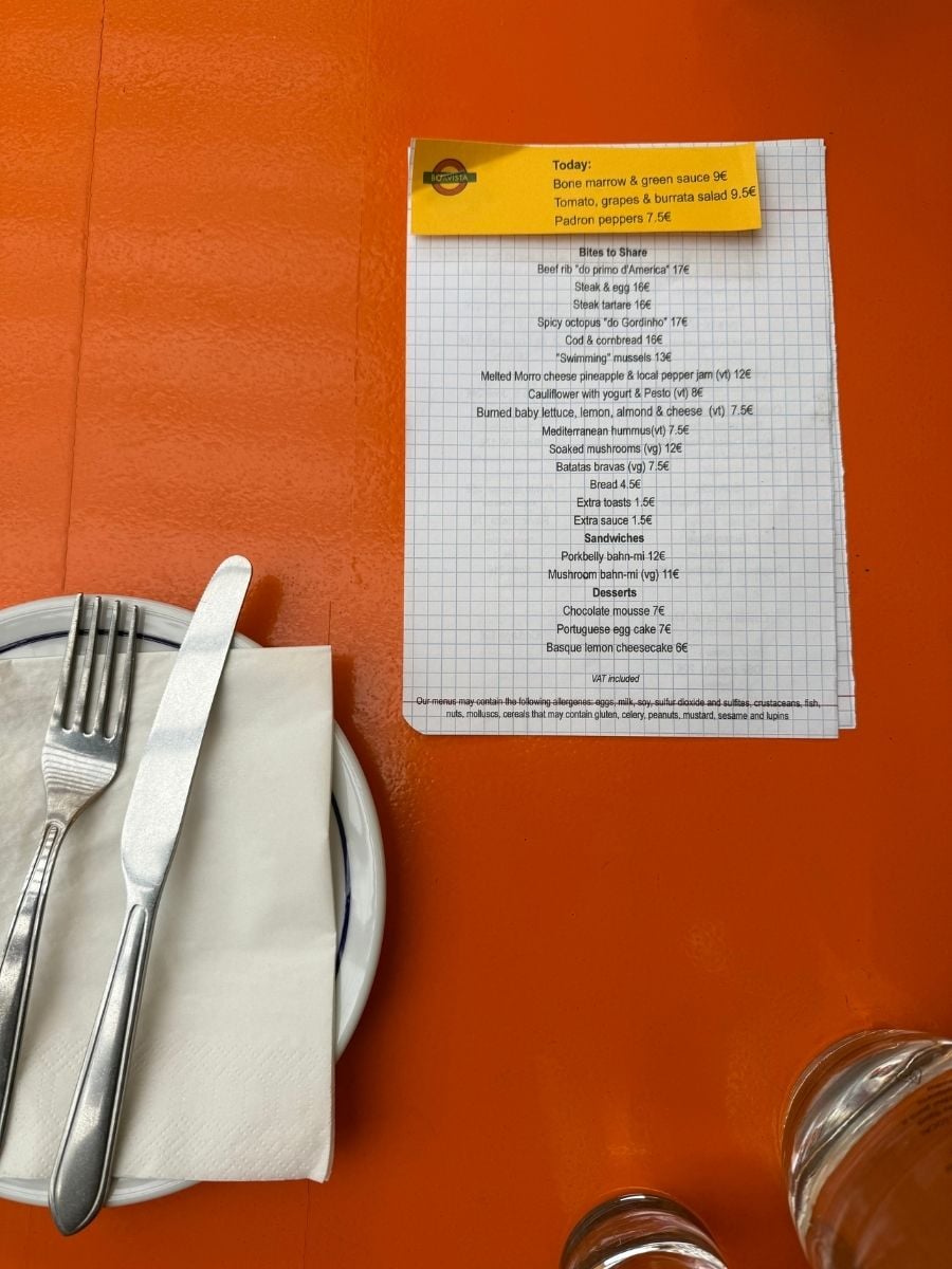Printed restaurant menu on an orange table with cutlery and glassware in Ponta Delgada, S&atilde;o Miguel, Azores showcasing local dishes and small plates