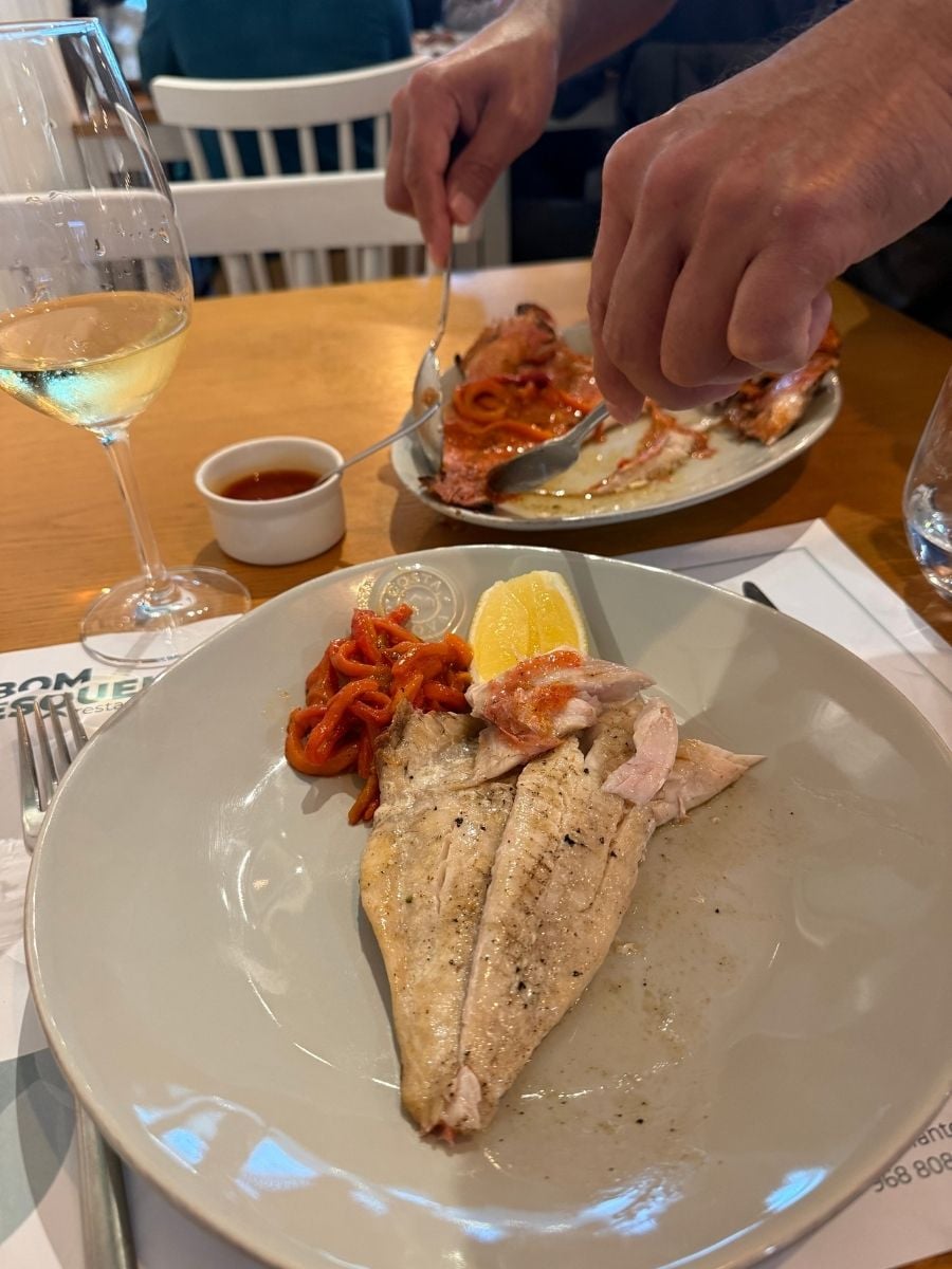 Grilled fish fillets with roasted peppers and lemon served at a casual restaurant in S&atilde;o Miguel, Azores with a glass of white wine on the table