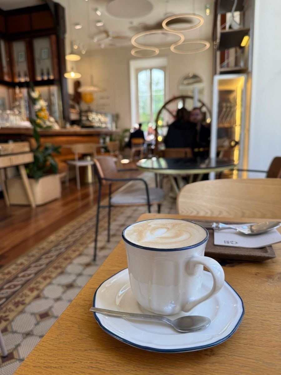 Cup of cappuccino on a wooden table in a cozy caf&eacute; in S&atilde;o Miguel, Azores with soft lighting and a relaxed indoor ambiance