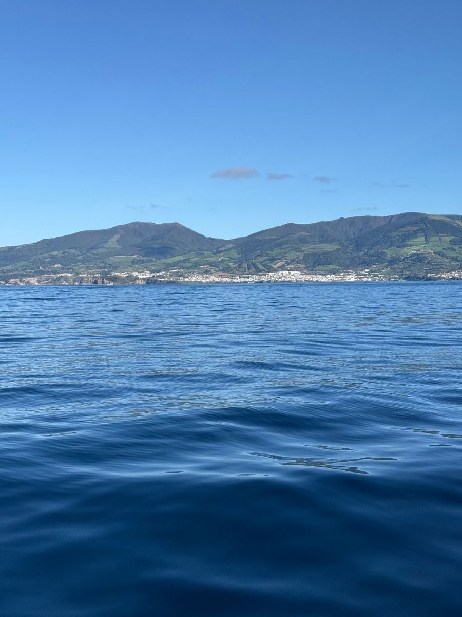 Calm ocean view facing green volcanic hills in S&atilde;o Miguel, Azores with gentle waves and a peaceful coastal atmosphere