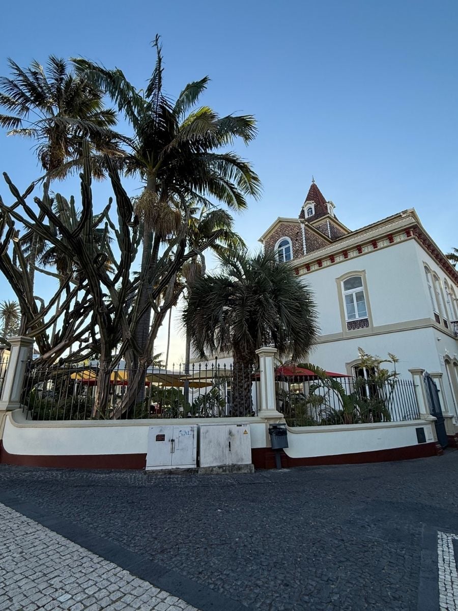 Historic villa with ornate architecture and palm trees in S&atilde;o Miguel, Azores surrounded by a lush garden and cobblestone street